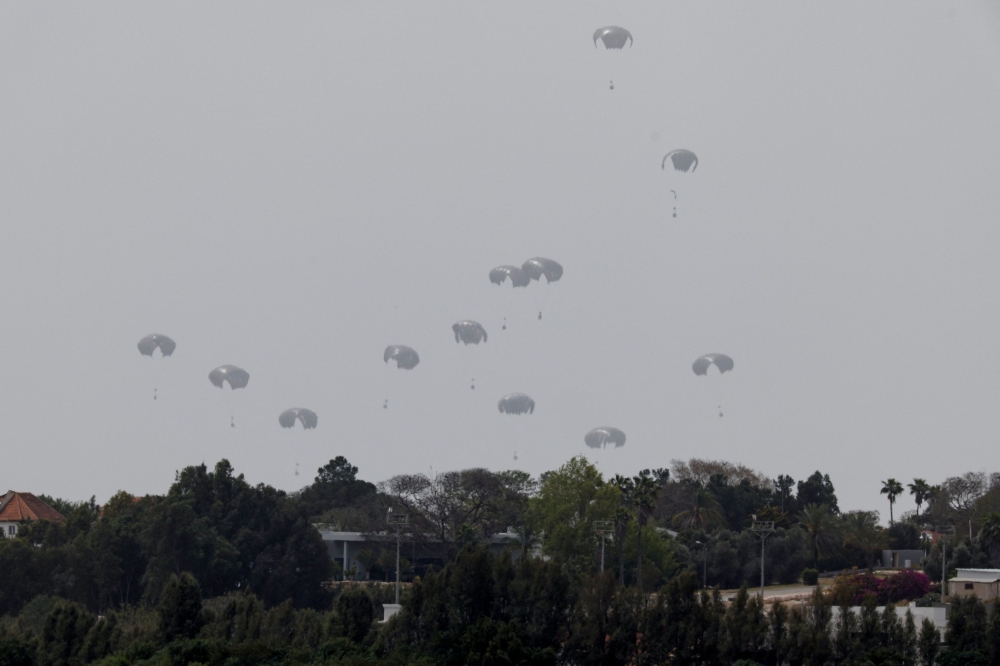 Humanitarian aid falls through the sky towards the Gaza Strip after being dropped from an aircraft, amid the ongoing conflict between Israel and the Palestinian Islamist group Hamas, as seen from Israel, April 25, 2024. — Reuters pic