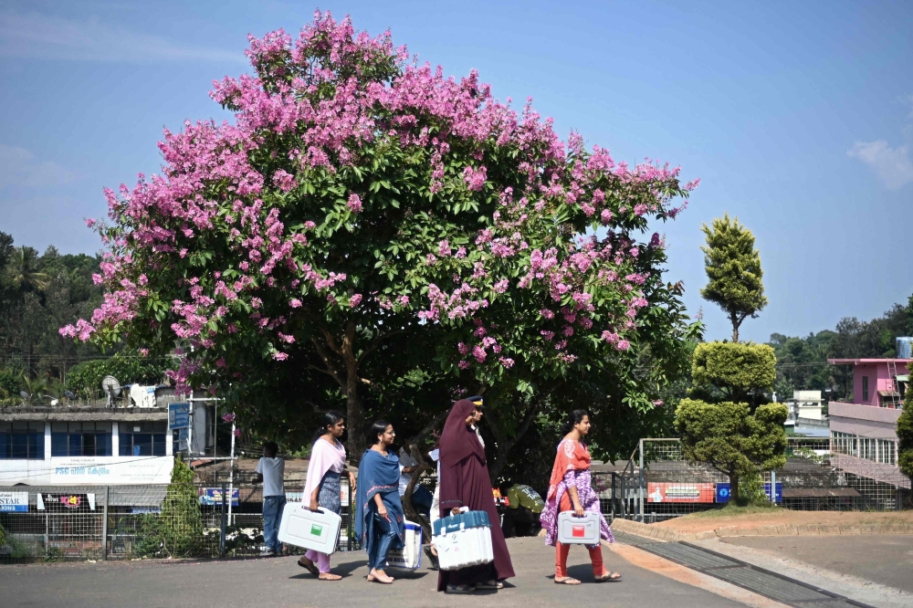 Officials carry Electronic Voting Machines (EVM) to a polling station in Wayanad district of Kerala state on April 25, 2024. — AFP pic