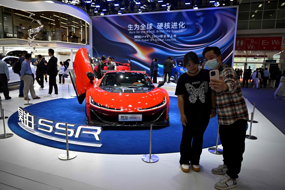 Visitors take pictures in front of a Hypar SSR model car displayed at the Beijing Auto Show April 26, 2024. — AFP pic