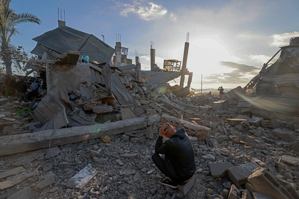 A man sits amid the debris of destroyed houses in the aftermath of Israeli bombardment in Rafah in the southern Gaza Strip February 22, 2024. — AFP pic