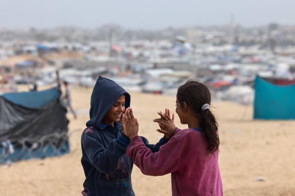 Displaced Palestinian children play hand clapping games at a tent camp in Rafah in the southern Gaza Strip April 26, 2024. — AFP pic
