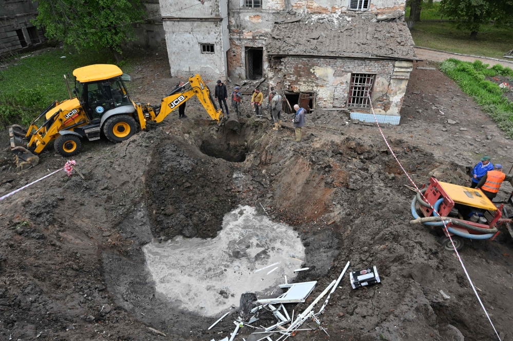 Utility workers operate next to a crater in the courtyard of a hospital in Kharkiv on April 27, 2024, as Russia launched a ‘massive’ missile strike at Ukraine overnight, damaging four power plants in the latest barrage targeting the country’s energy supply, officials in Kyiv said yesterday. — AFP pic 