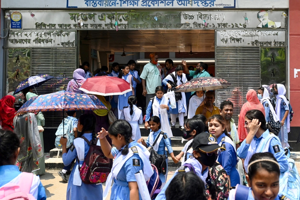Students leaving their school compound carry umbrellas on a hot summer day in Dhaka on April 28, 2024, amid the ongoing heatwave. Millions of students returned to their reopened schools across Bangladesh on April 28, despite a lingering heatwave that prompted a nationwide classroom shutdown order last weekend. — AFP pic 