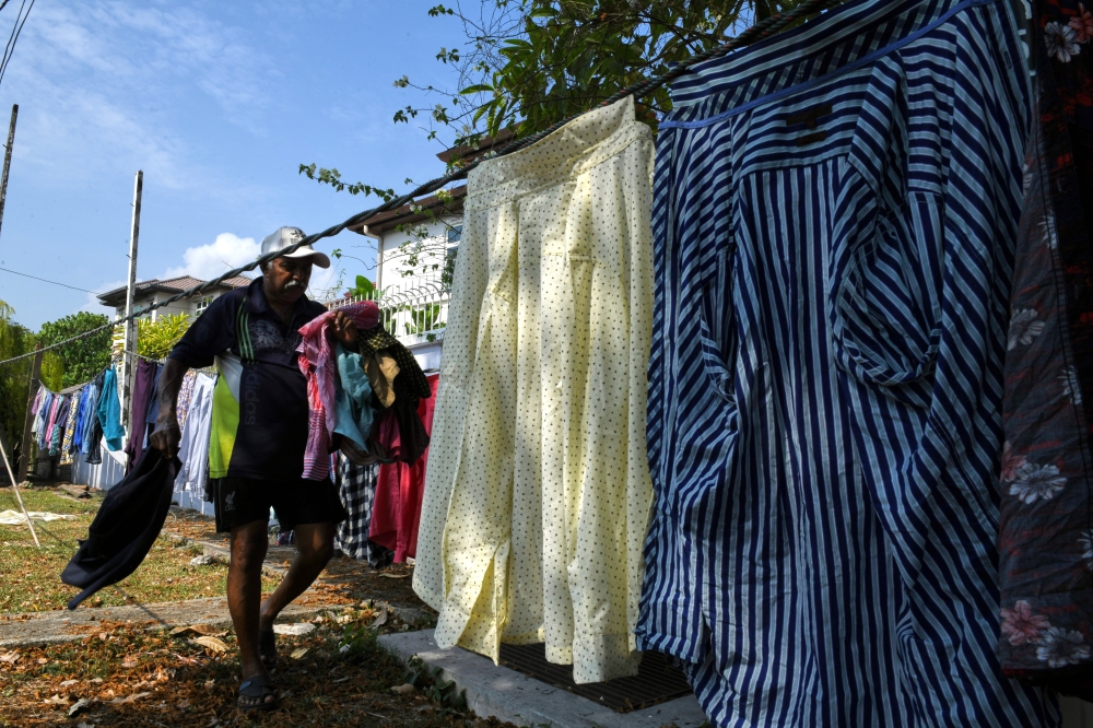Third-generation dhobi man Raman Angko hanging up laundry to dry. — Bernama pic