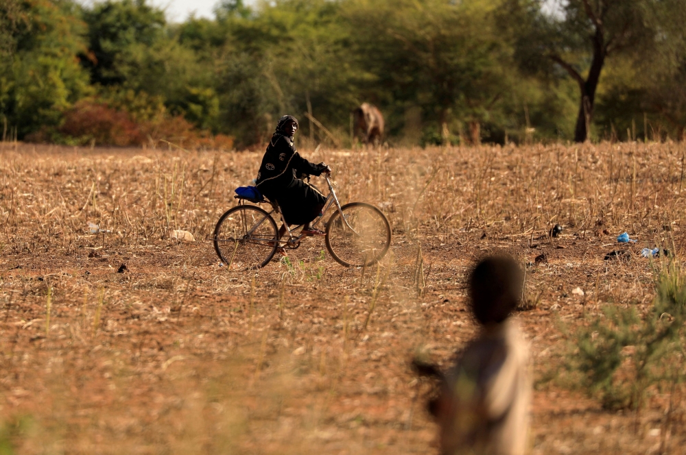 A child who fled with his parents from attacks of armed militants in the Sahel region watches a woman on a bicycle at a camp for internally displaced people (IDPs) in Kaya, Burkina Faso November 23, 2020. — Reuters file pic 