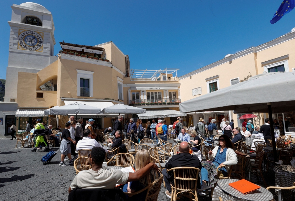 People sit at the tables outside restaurants and cafes on Capri Island, Italy, April 18, 2024. — Reuters pic  