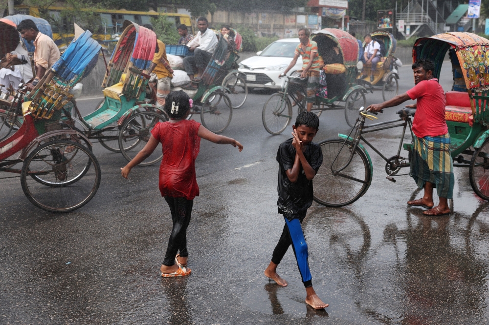 Children cool themselves in the water, sprayed from a spray cannon by Dhaka North City Corporation, during a countrywide heatwave in Dhaka, Bangladesh, April 28, 2024. — Reuters pic
