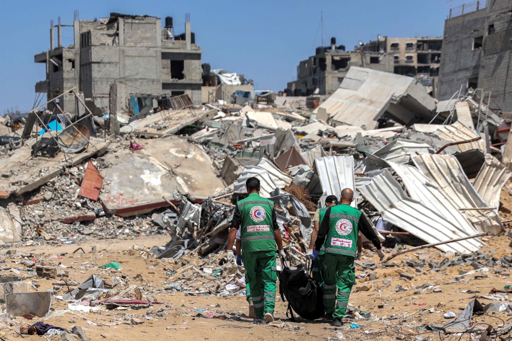 Palestinian paramedics carry away bodies of dead people uncovered in the vicinity of Al-Shifa Hospital in Gaza City on April 17, 2024 after the recent Israeli military operation there. — AFP pic