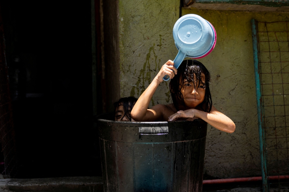 Children take a bath in a bucket during a hot day in Manila, Philippines, April 25, 2024. — Reuters pic