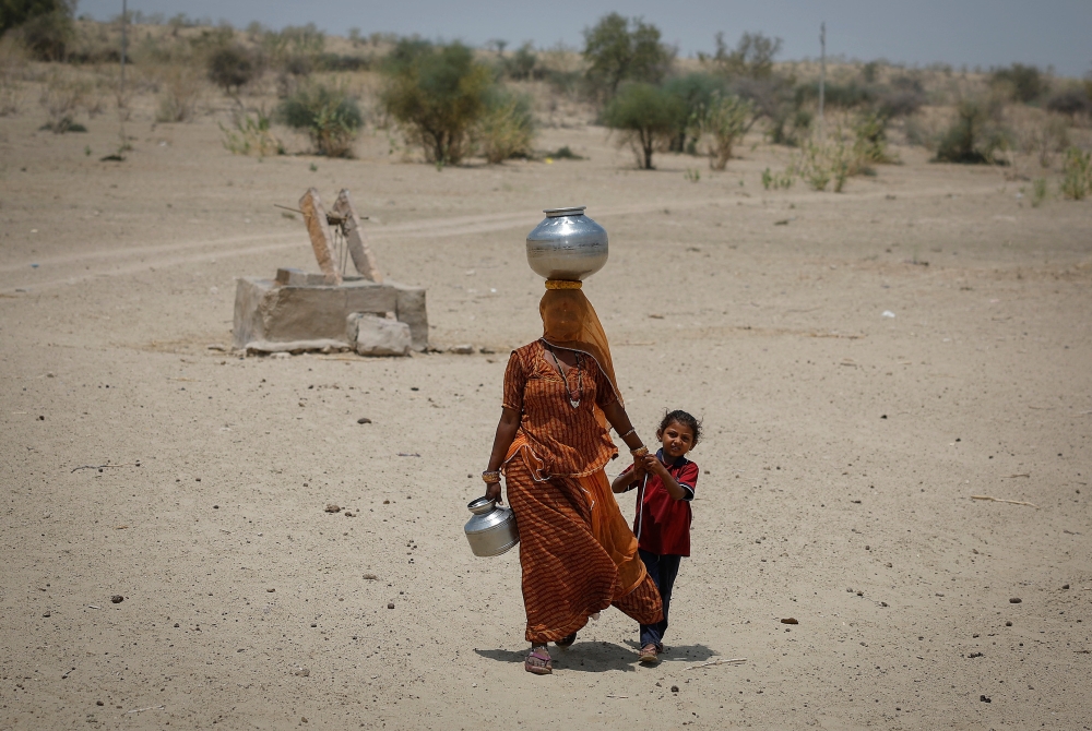 A woman walks back towards her home after filling water from a shallow well in a desert area on a hot summer day in Barmer, Rajasthan, India April 26, 2024. — Reuters pic  