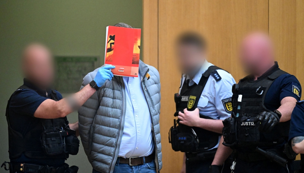 A defendant in handcuffs arrives in a courtroom were nine men go on trial charged with high treason, attempted murder and plotting a violent coup d'etat aimed at installing an aristocrat as national leader and imposing martial law, in Stuttgart, Germany, April 29, 2024. — Bernd Weißbrod/Pool/Reuters pic