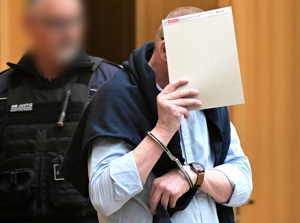 A defendant in handcuffs arrives in a courtroom were nine men go on trial charged with high treason, attempted murder and plotting a violent coup d'etat aimed at installing an aristocrat as national leader and imposing martial law, in Stuttgart April 29, 2024. — Bernd Weißbrod/Pool/Reuters pic