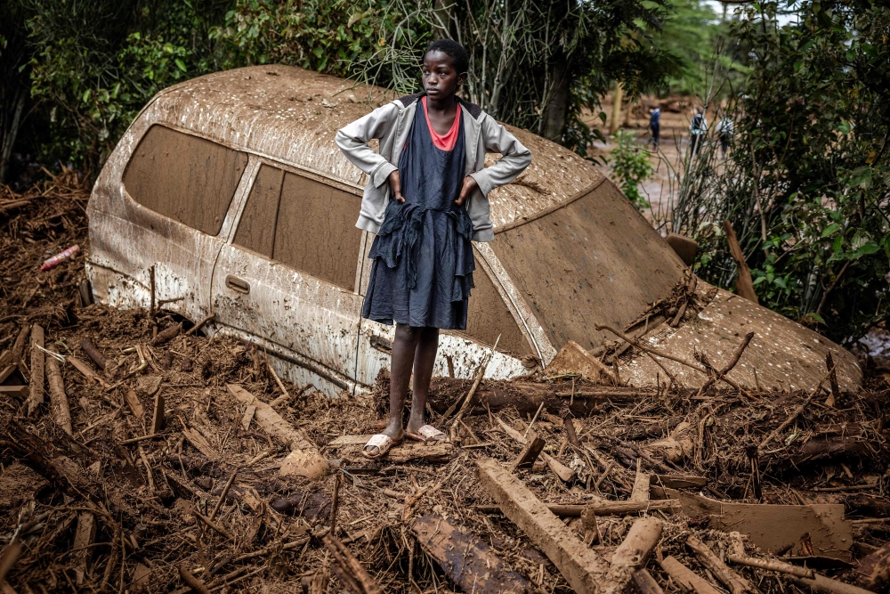 A girl looks on next to a damaged car buried in mud in an area heavily affected by torrential rains and flash floods in the village of Kamuchiri, near Mai Mahiu, on April 29, 2024. — AFP pic