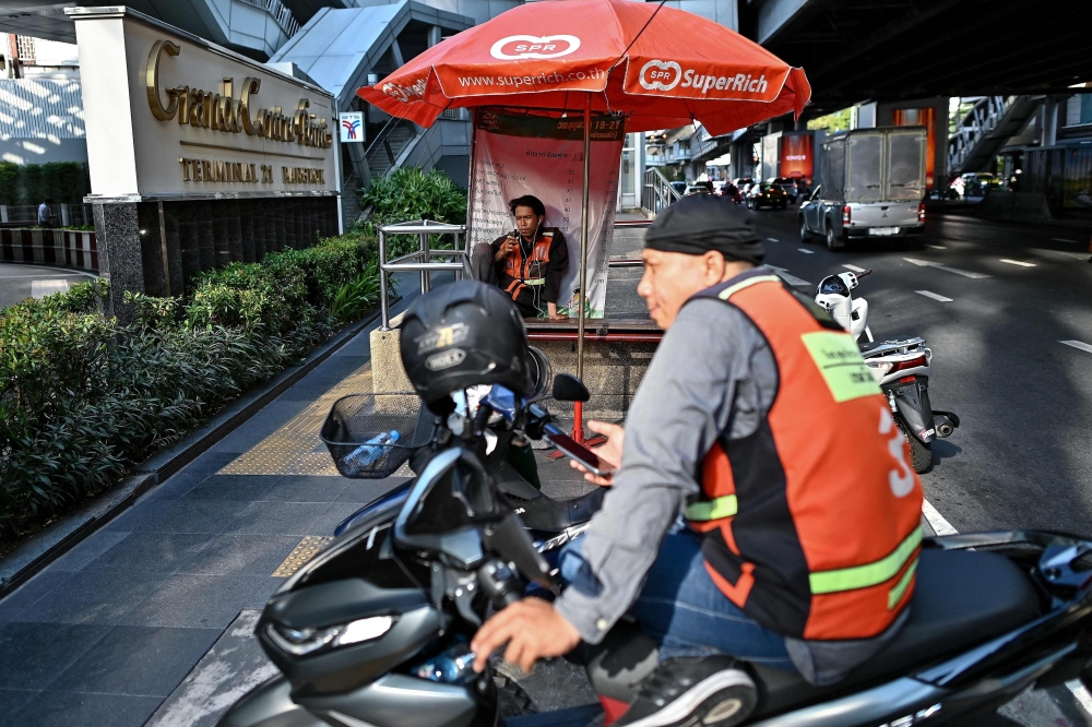 A motorbike taxi driver takes shelter from the sun under an umbrellas as he waits for customers in Bangkok on April 29, 2024. — AFP pic