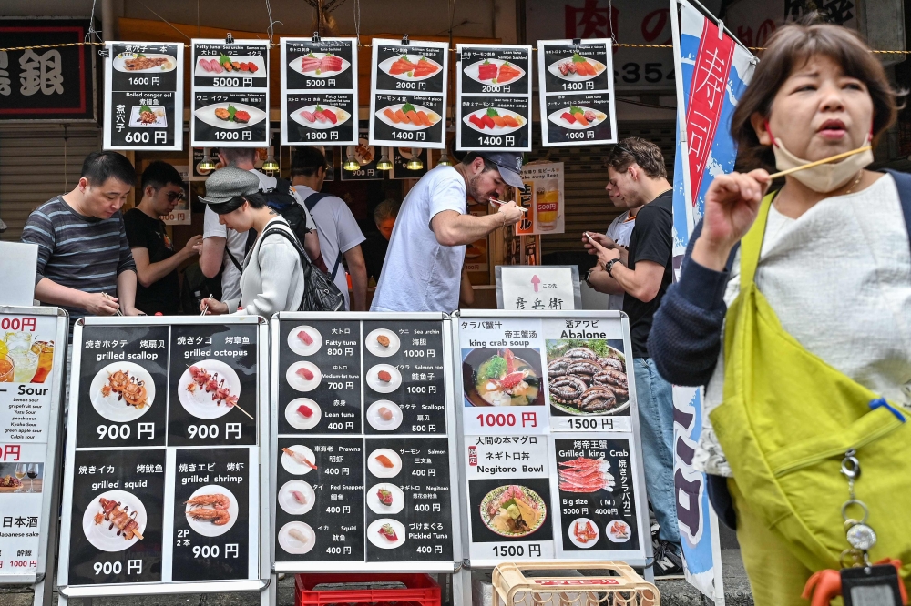 Visitors eat seafood during lunchtime at the popular tourist area of Tsukiji fish market in central Tokyo as the country marks the ‘Golden Week’ holidays April 30, 2024. — AFP pic