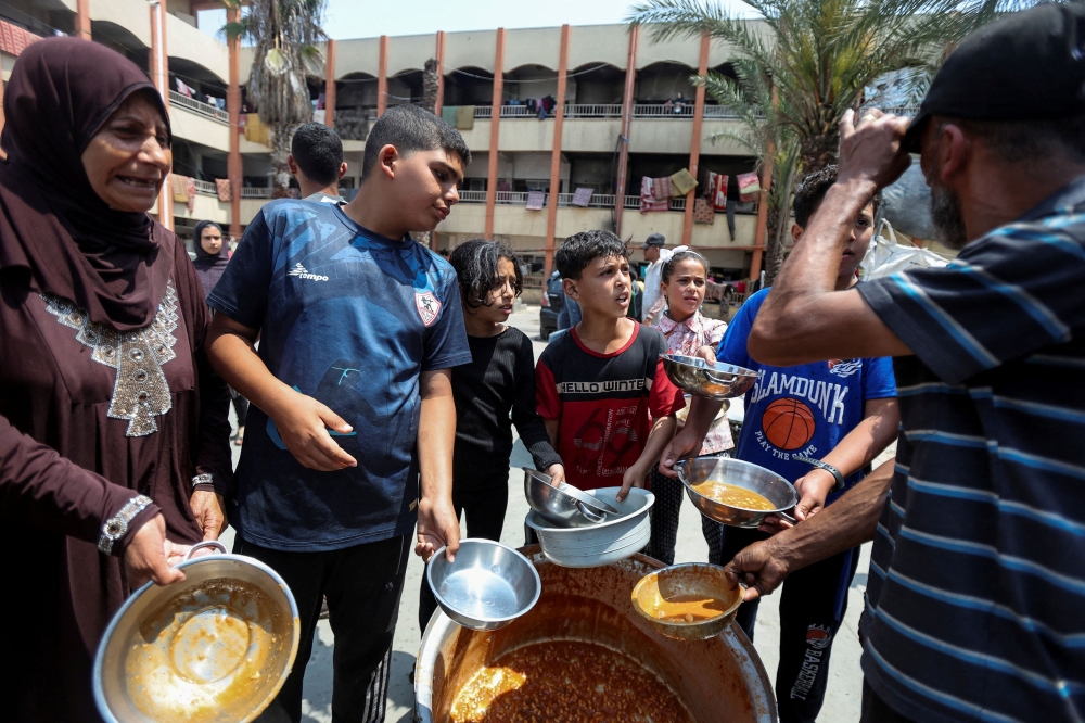 Palestinians gather to receive food meals cooked by World Central Kitchen (WCK) after the charity resumed operations, at a school sheltering displaced people, amid the ongoing conflict between Israel and Hamas, in Deir Al-Balah in the central Gaza Strip May 1, 2024. — Reuters pic