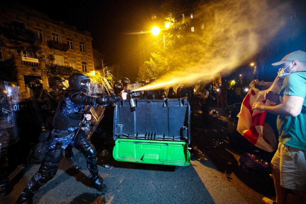 Riot police use pepper spray to disperse protesters during a rally against a controversial 