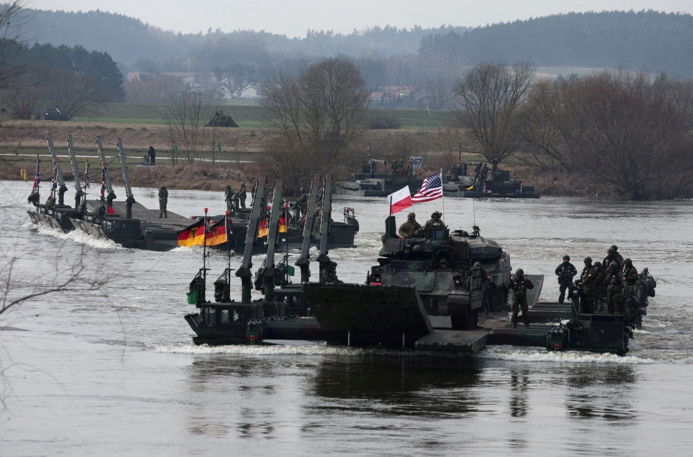 German soldiers transport US soldiers in an M2 Bradley infantry fighting vehicle as they cross Vistula River during Nato Dragon-24, part of the Steadfast Defender 2024 exercise, in Korzeniewo, Poland, March 4, 2024. ― Reuters pic