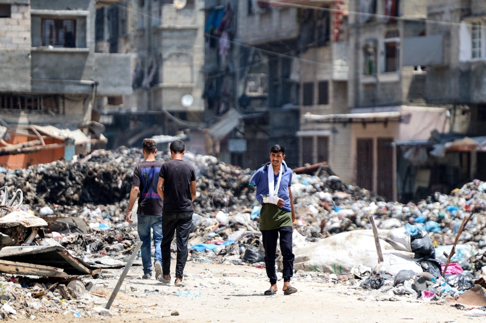 An injured Palestinian man walks near a rubbish dump in Gaza City on May 3, 2024, amid the ongoing conflict between Israel and the militant group Hamas. ― AFP pic