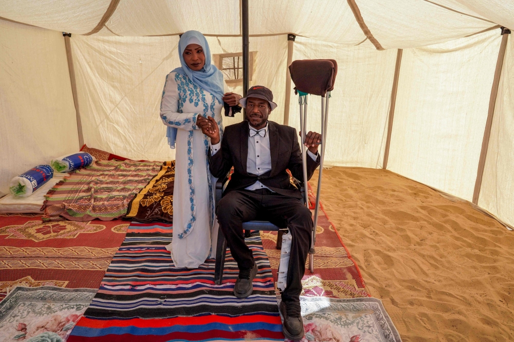 A bride and groom pose for a picture inside a tent ahead of a mass wedding ceremony in Khan Younis, in the southern Gaza Strip, on May 3, 2024, amid the ongoing conflict between Israel and the Palestinian militant group Hamas. ― AFP pic