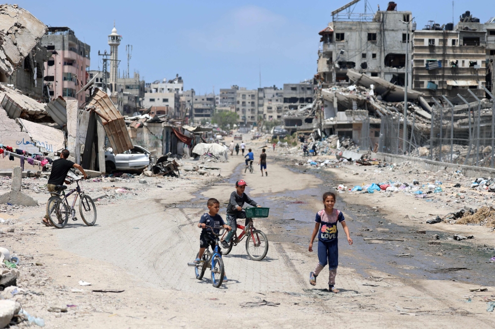 File photo of Palestinian children riding their bicycles along a street devastated by Israeli bombardment in Gaza City on May 3, 2024, amid the ongoing conflict between Israel and the militant group Hamas. ― AFP pic