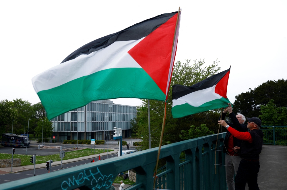 Demonstrators affix Palestinian flags to an overpass ahead of a rally at television station RTE’s studios calling for Ireland’s national broadcaster to boycott the Eurovision Song Contest because of the Israeli entry, amid the ongoing conflict between Israel and the Palestinian Islamist group Hamas, in Dublin, Ireland, May 2, 2024. ― AFP pic