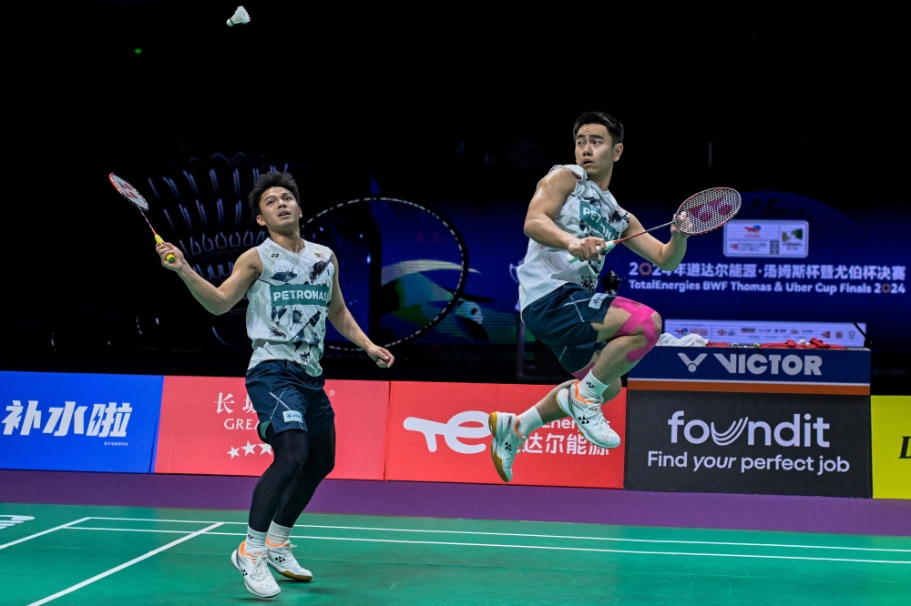 Malaysia's Goh Sze Fei and Nur Izzuddin (left) hit a return to China's He Jiting and Ren Xiangyu during their men’s doubles semi-final match at the Thomas and Uber Cup badminton tournament in Chengdu May 4, 2024. — AFP pic