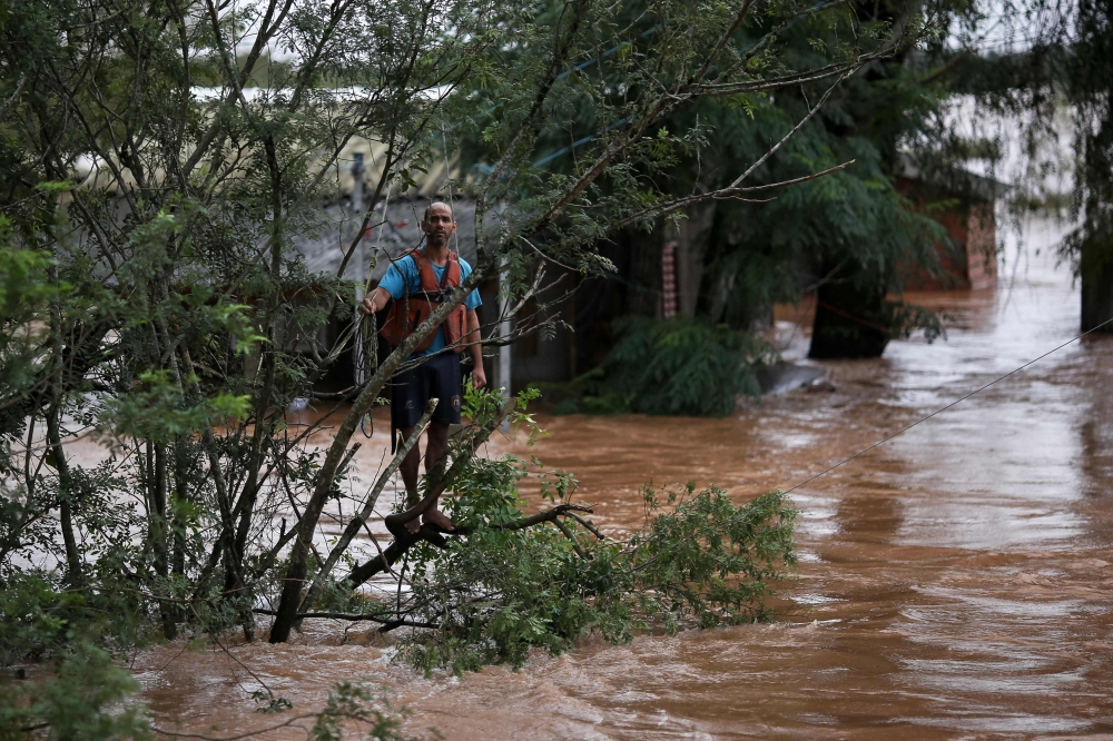 A resident hangs on a tree while waiting for a rescue team. — AFP pic