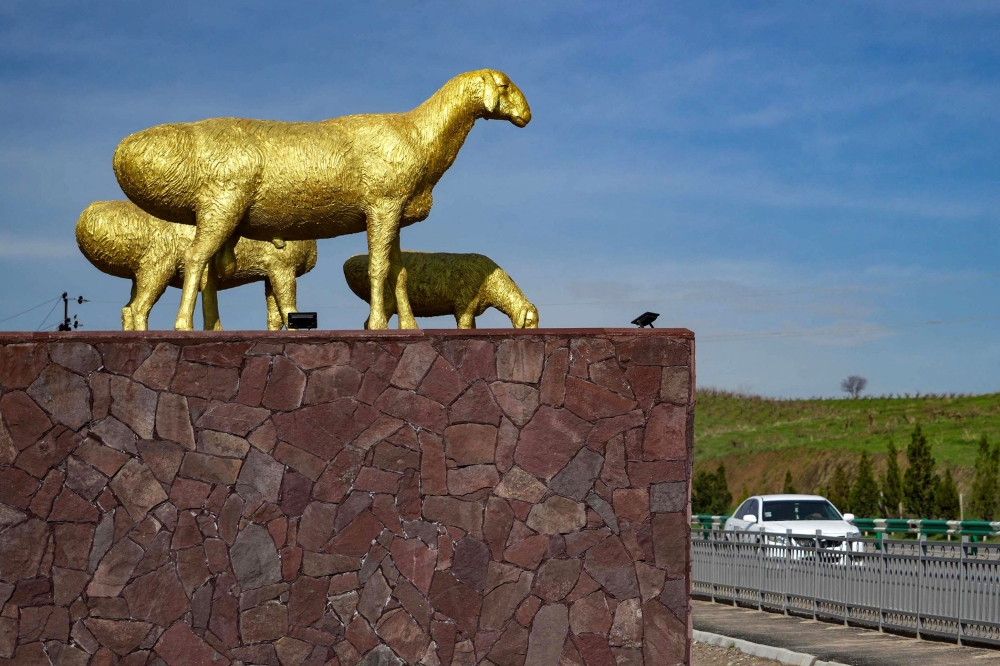 A car drives past a golden-coloured monument representing three Hissar sheep, near the town of Hissar, western Tajikistan March 27, 2024. — AFP pic