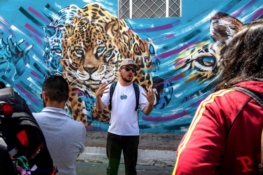 The tourist guide May Rojas (centre) talks with tourists during a tour of the Ciudad Bolivar neighbourhood in Bogota April 14, 2024. 