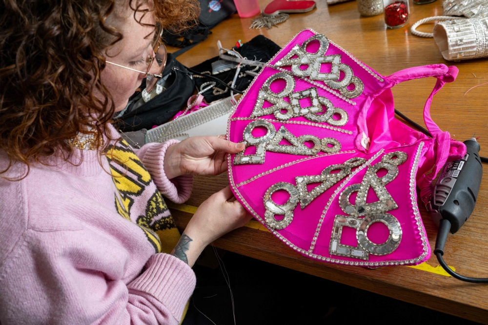 An employee works on a costume used by dancers, at the design studio of the Moulin Rouge musical cabaret in Paris on March 13, 2024. — AFP pic