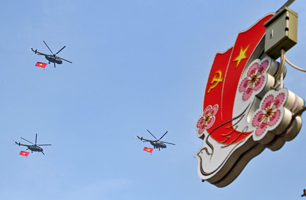 Helicopters with Vietnamese and Communist flags fly above Dien Bien Phu city on May 5, 2024, as Vietnam prepares to commemorate the 70th anniversary of the victory against French colonial forces. — AFP pic