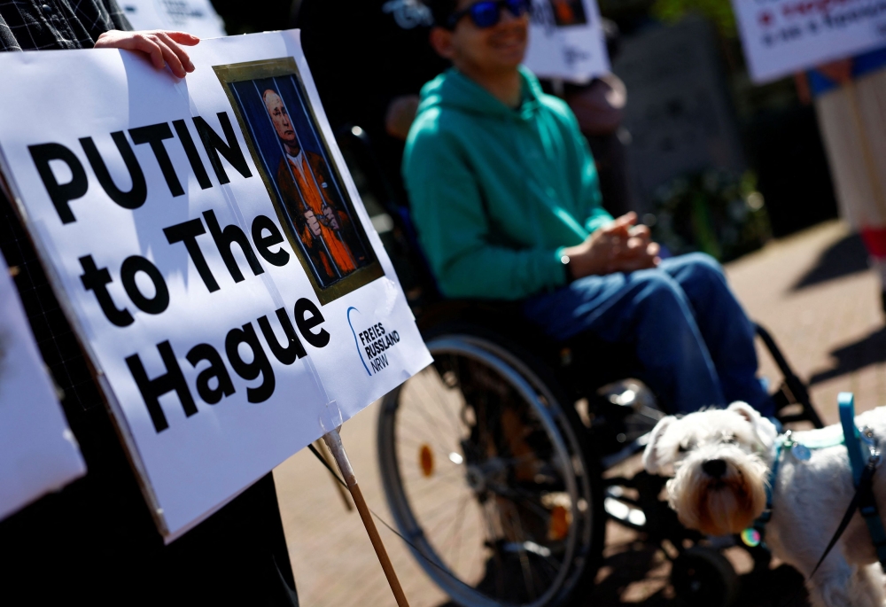 A protester holds a placard as people gather in front of the Peace Palace to call for Russian President Vladimir Putin to go to jail instead of another term in the Kremlin, on the day of Putin's swearing-in for a new six-year term as president, in The Hague, Netherlands, May 7, 2024. — Reuters pic