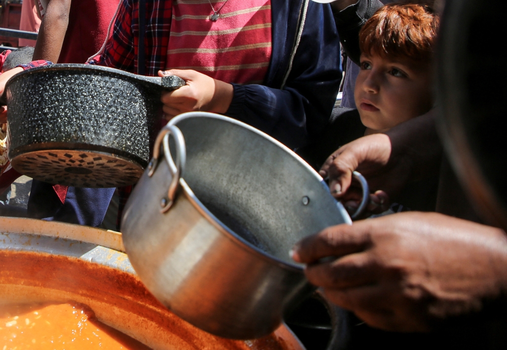 Palestinians gather to receive food cooked by a charity kitchen, amid shortages of aid supplies, after Israeli forces launched a ground and air operation in the eastern part of Rafah, as the ongoing conflict between Israel and Hamas continues, in Rafah, in the southern Gaza Strip May 8, 2024. — Reuters pic
