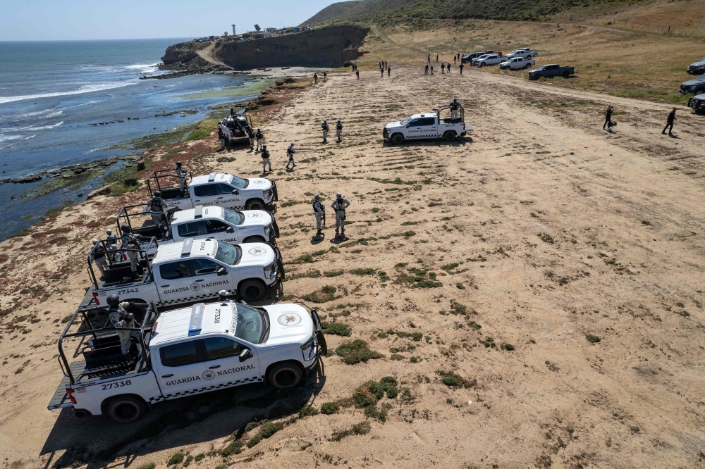 An aerial view of National Guard vehicles guarding as state prosecutors search at the site where three surfers were camping before disappearing last week. — AFP pic