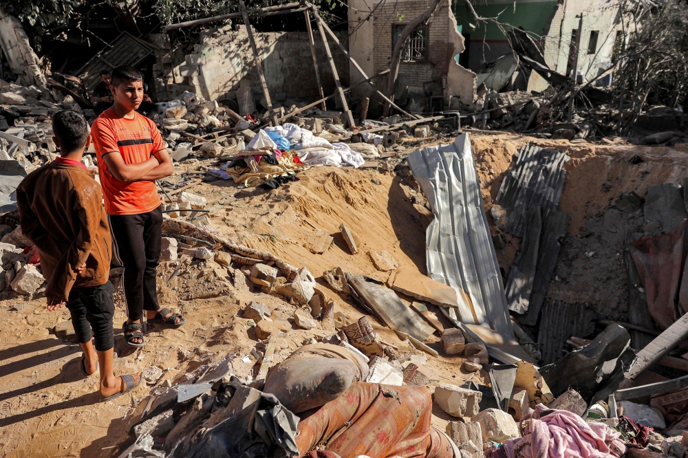 Children stand next to the site of a building that was hit by Israeli bombardment in Rafah. — AFP pic