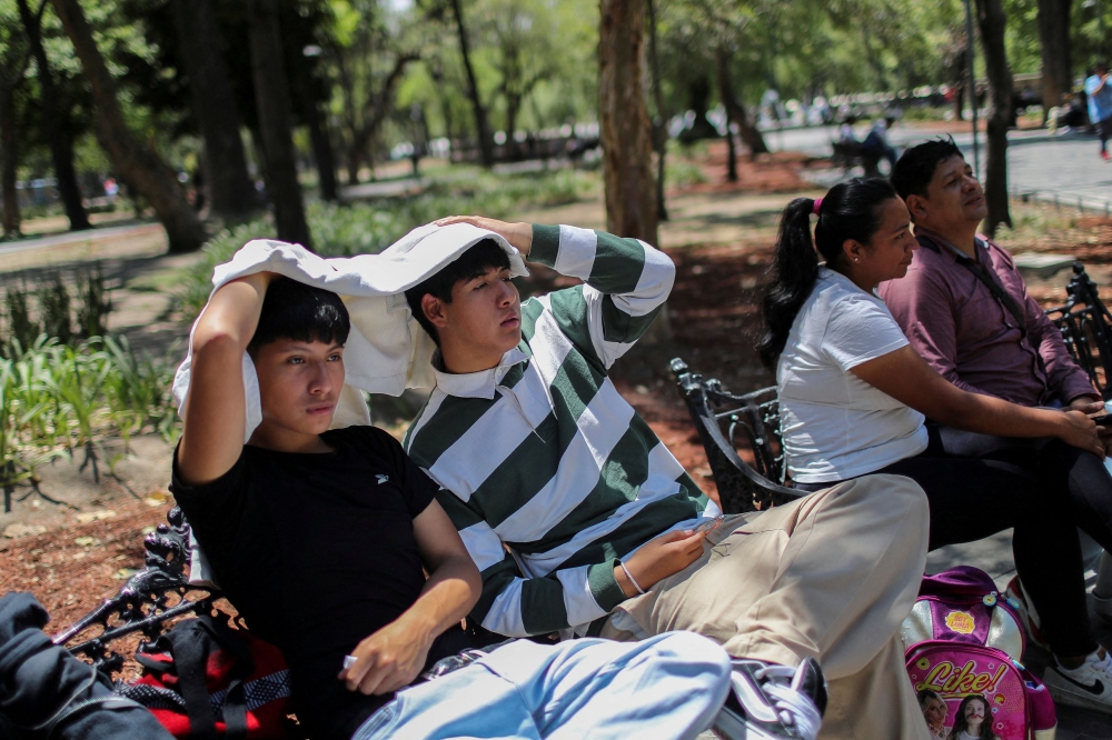Men use a sweatshirt to protect themselves from the sun during a heat wave in Mexico City April 16, 2024. — Reuters pic