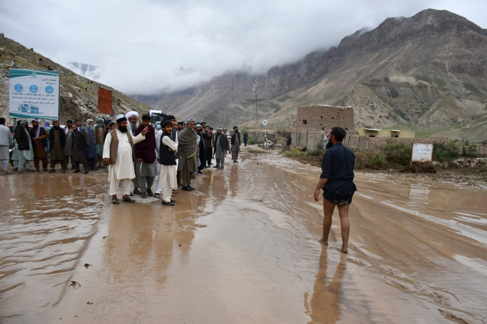Afghan people gather along a road between Samangan and Mazar-i-Sharif covered in mud following a flash flood after heavy rainfall, in Feroz Nakhchir district of Samangan Province on May 11, 2024. — AFP pic
