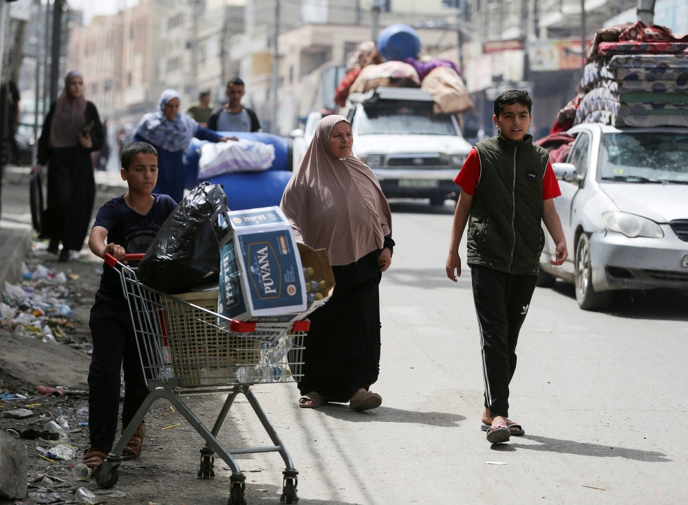 A Palestinian boy pushes a shopping trolley, as vehicles loaded with belongings evacuate, after Israeli forces launched a ground and air operation in the eastern part of Rafah, amid the ongoing conflict between Israel and Hamas, in Rafah, in the southern Gaza Strip, May 11, 2024. — Reuters pic