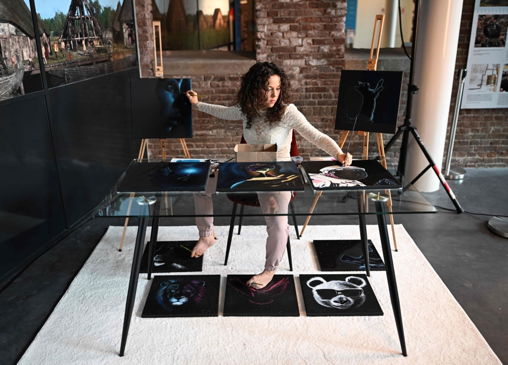Dutch artist Rajacenna van Dam, poses in a museum in Vlaardingen, on May 3, 2024, as paints ten paintings at once with both hands and feet. — AFP pic