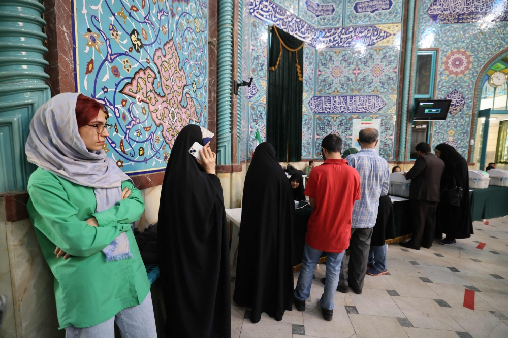 Iranians queue to vote at a polling station in Tehran during the parliamentary runoff elections on May 10, 2024. — AFP pic