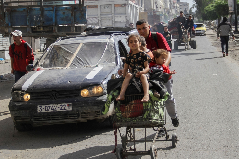 A displaced Palestinian man, who fled Jabalia after the Israeli military called on residents to evacuate, pushes children in a trolley as they make their way towards Gaza City, amid the ongoing conflict between Israel and Hamas, May 12, 2024. — Reuters pic