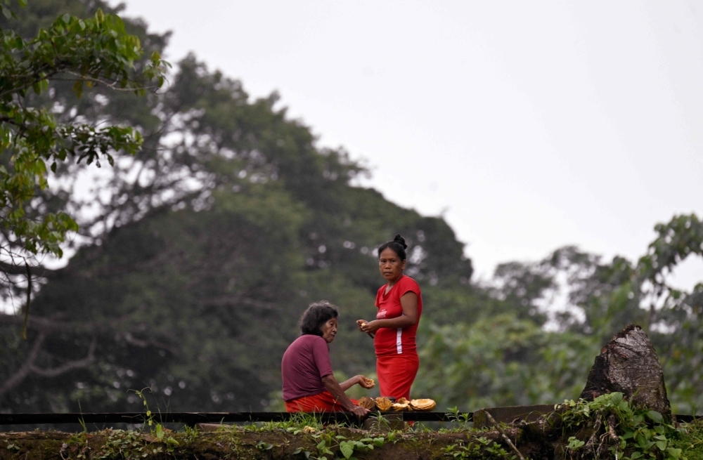 Two indigenous women eat fruits in the protected Amazon rainforest of Cuyabeno, Ecuador March 29, 2024. — AFP pic