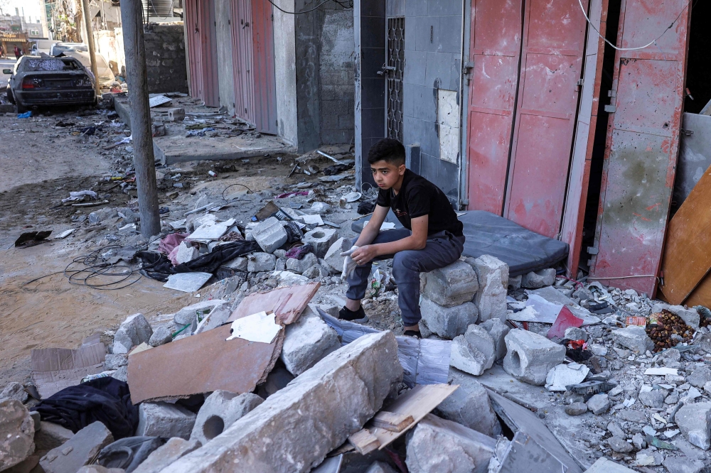 A boy sits amidst rubble at the site of a building that was hit by Israeli bombardment in Rafah. — AFP pic 