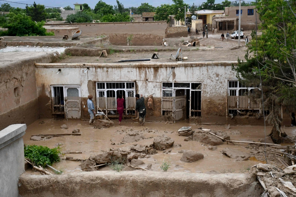 Afghan men clear mud from a house following flash floods after heavy rainfall at a village in Baghlan-e-Markazi district of Baghlan province on May 11, 2024. — AFP pic