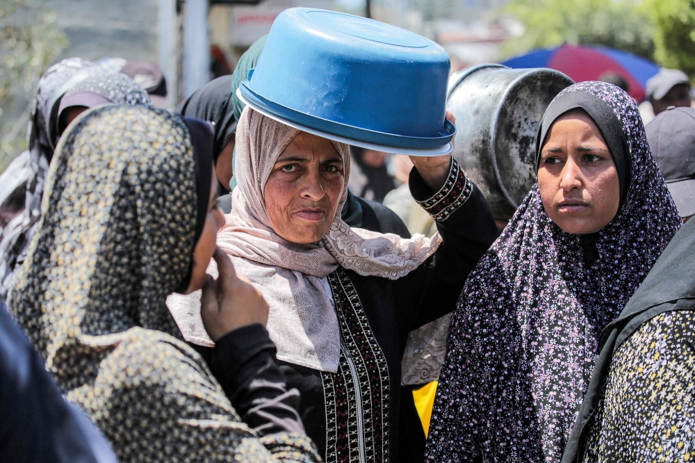 Women queue to receive food rations from a public kitchen in Deir el-Balah. — AFP pic