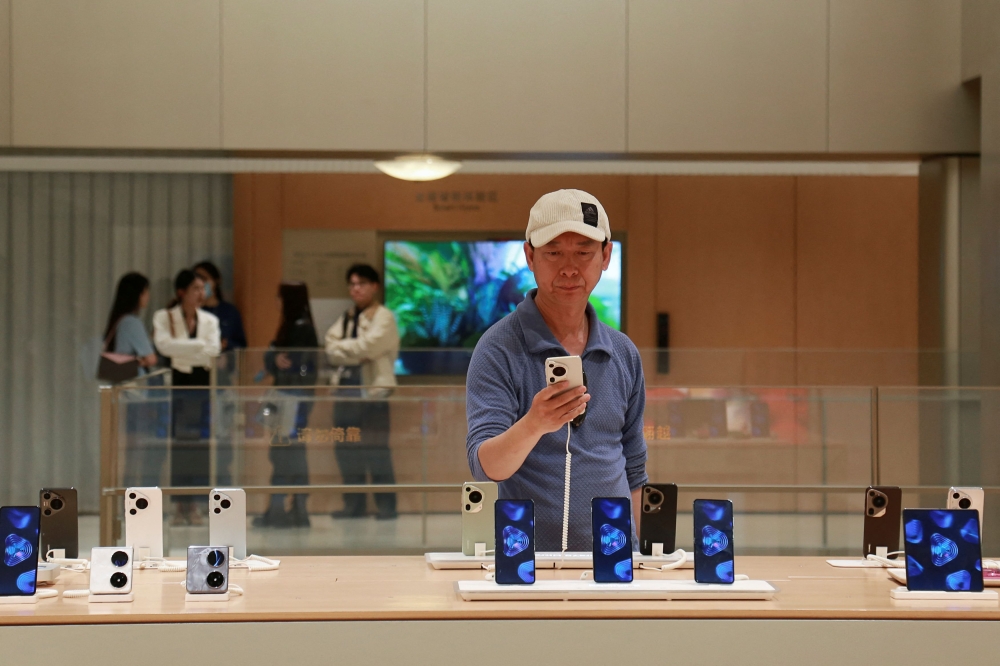 A man looks at a smartphone on display at Huawei's flagship store in Shanghai. — Reuters pic