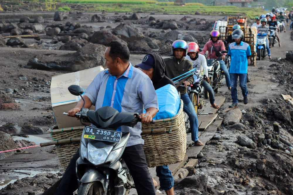 People drive their motorcycles over wooden slabs to avoid the mud in Rambatan Village, Tanah Datar. — AFP pic