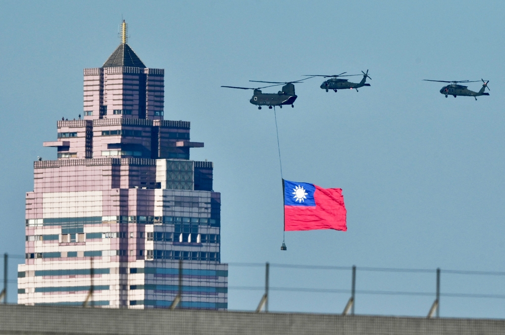 A US-made CH-47SD helicopter flies a national flag past a building during a rehearsal ahead of the May 20 Taiwan President-elect Lai Ching-te inauguration ceremony in Taipei. — AFP pic