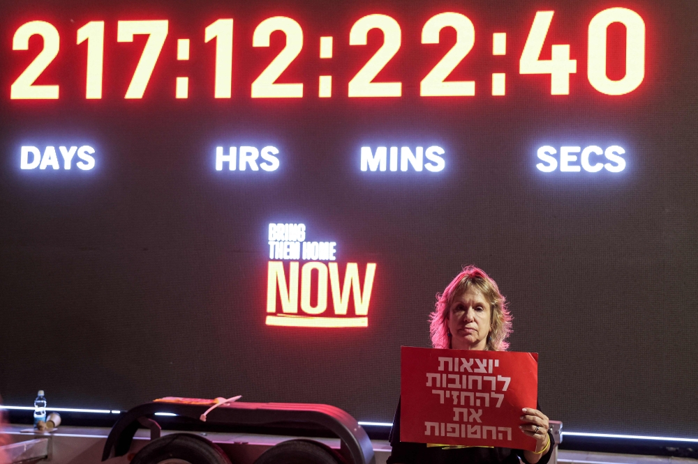 A woman stands before a clock counting the number of days, hours, minutes, and seconds since hostages were taken captive in Gaza during the October 7 attacks by Palestinian militants. — AFP pic